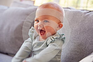 Cute Baby Girl Sitting On Sofa Playing Laughing And Smiling