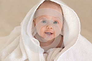 Cute baby girl smiling in white towel. Funny face