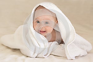 Cute baby girl smiling in white towel. Funny face