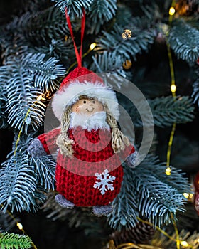 Cute baby girl snowman handmade. Red knitted fur coat and hat, cotton braids. Snow maiden doll hanging on a branch of a christmas