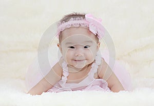 Cute baby girl on a soft white carpet. In a beautiful pink dress