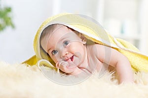 Cute baby girl sucking her thumb. Child lying under towel.