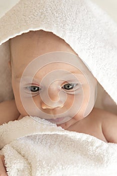 Cute baby girl in white towel. Sad face