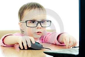 Cute baby with glasses looking into the laptop