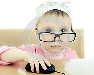 Cute baby with glasses looking into the laptop