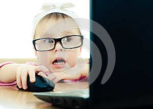 Cute baby with glasses looking into the laptop