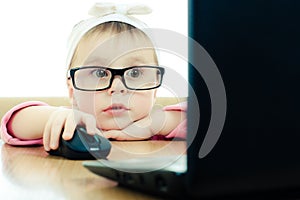 Cute baby with glasses looking into the laptop