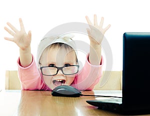 Cute baby with glasses looking into the laptop