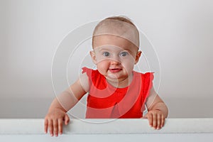 Cute baby having fun, standing in crib. Happy baby. Baby emotions. Baby smile