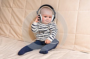 Cute baby with headphones listens to music at home