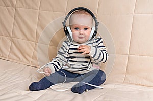 Cute baby with headphones listens to music at home