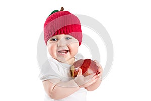 Cute baby in a knitted apple hat biting in a red ripe apple, isolated on white