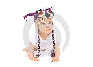 Cute baby in knitted hat crawls on white background