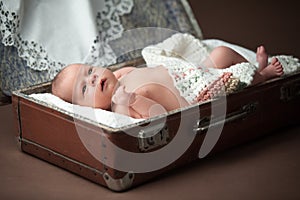 Cute baby laying in suitcase.