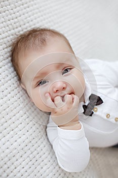 Cute baby lies and crawls on a white bed in a bright bedroom alone.