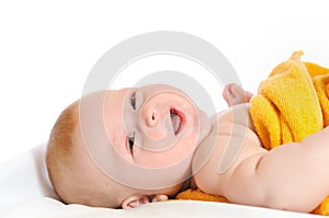 Cute baby lies under yellow blanket