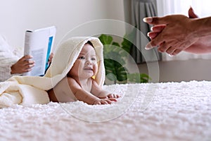 Cute baby looking at hand his father under white blanket. Innocence baby with parent crawling on white bed with towel on