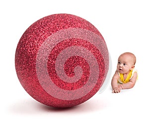 Cute Baby looking at a Huge Christmas Ornament on white