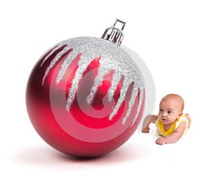 Cute Baby looking at a Huge Christmas Ornament on white