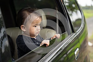 Cute baby looks outside while standing in the car with the windows open