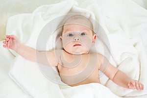 Cute baby lying on back in bathing towel