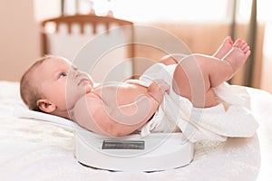 Cute baby lying on the scales in his bedroom