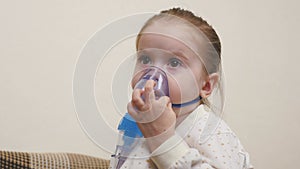 A cute baby in a mask is breathing through an inhaler. Home inhalation procedure. The child is receiving respiratory