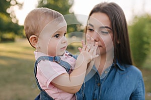 Cute baby on mom`s hands outside. Family in the park in summer. Denim style. Mom and daughter in jeans