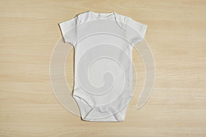 Cute baby onesie on wooden background photo