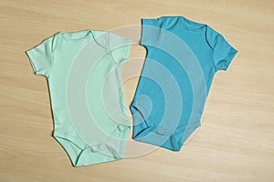 Cute baby onesies on wooden , top view