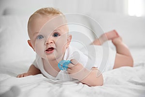 Cute baby with pacifier lying on bed
