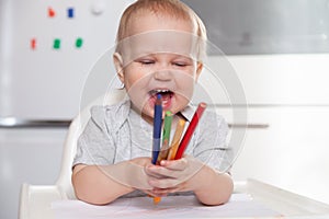 Cute baby paint using colorful pencils on white table