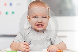 Cute baby paint using colorful pencils on white table