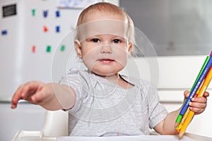 Cute baby paint using colorful pencils on white table