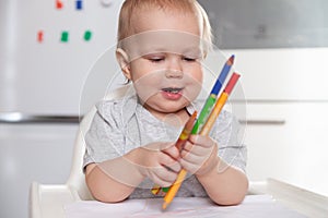 Cute baby paint using colorful pencils on white table