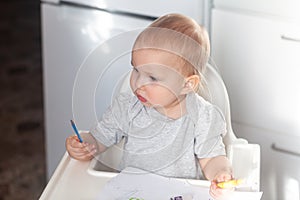 Cute baby paint using colorful pencils on white table