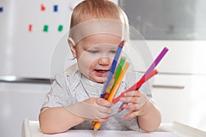 Cute baby paint using colorful pencils on white table