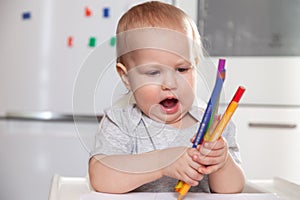 Cute baby paint using colorful pencils on white table