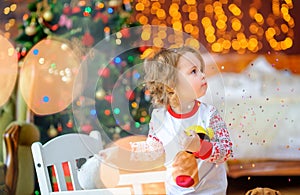 Cute baby in pajamas plays in a festively decorated room