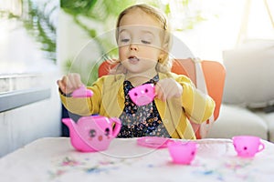 Cute baby play with pink tea cup at home