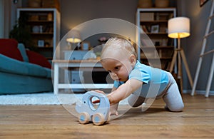 Cute baby playing with elephant toy with wheels sitting on floor play in sunny living room. Toys for little kids. Interior for