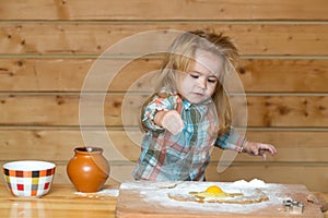 Cute baby playing with flour at wooden kitchen. Child cooking.
