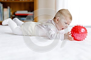 Cute baby playing with red gum ball, crawling, grabbing