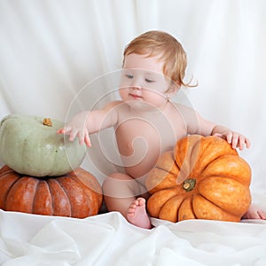 Cute baby posing on the background of pumpkins. Thanksgiving greetings