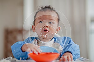 Cute baby with rice grains stuck to his face
