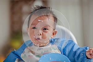 Cute baby with rice grains stuck to his face