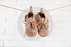 Cute baby shoes drying on washing line against white brick wall