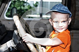 Cute baby sitting behind the wheel of an old jeep
