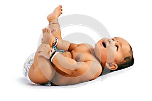 Cute baby sleeping on bed holding his feet and laughing, Pune, Maharashtra