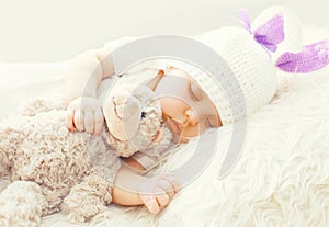 Cute baby sleeping with teddy bear toy on white soft bed